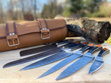 6 piece set of Damascus steel kitchen chef knives with a leather sheath on a wooden surface outdoors.