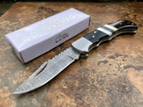 Knife with Damascus steel blade and black handle on a textured surface, next to a branded box.