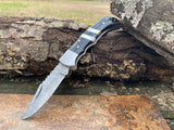 Ebony Tide Buffalo Horn and Mother of Pearl Folding Pocket Knife with a Damascus steel blade on a wooden surface