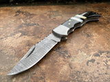 Ebony Tide Buffalo Horn and Mother of Pearl Folding Pocket knife with a Damascus steel blade on a textured surface