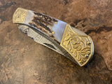 Handmade Damascus Steel Engraved Bolster folding pocket knife with gold and silver blade on a textured surface