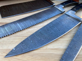 Three damascus steel chef knives on a wooden surface