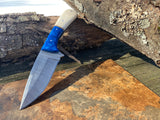 Handmade Damascus hunting & skinning knife with a Damascus steel blade and off-white camel bone handle with a blue acrylic bolster on a wooden surface