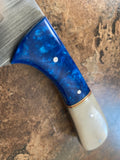 Damascus knife's camel bone handle with sapphire blue acrylic bolster on a textured surface
