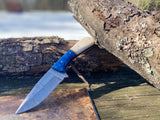 Handmade Damascus hunting & skinning knife with full tang Damascus steel blade and camel bone handle with a blue acrylic bolster on a wooden surface
