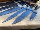 Set of kitchen chef knives with damascus steel blades on a wooden surface