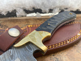 Knife with a Black Micarta handle highlighting a  brass bolster and leather sheath on a textured surface with snow in the background