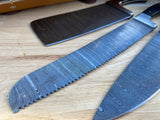 Two large kitchen knives with Damascus steel blades on a wooden surface.
