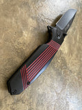 Folding knife with black and red design on a textured surface