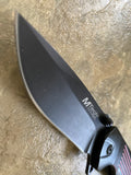 Knife with a black blade and black handle with red accents on a textured surface